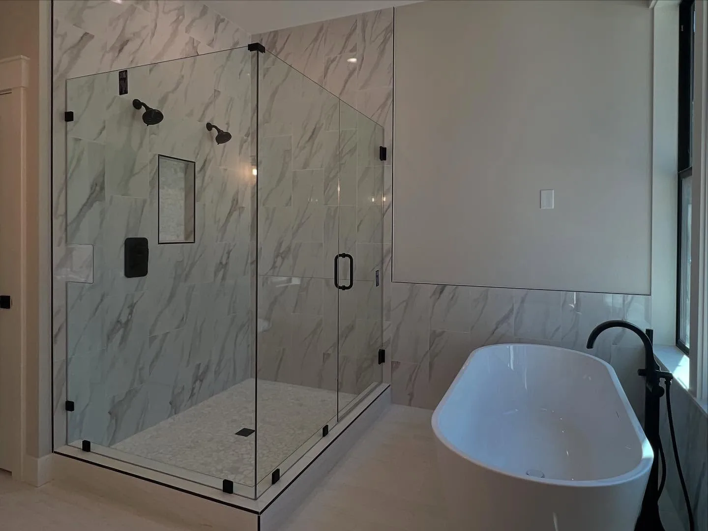 Frameless marble shower enclosure with matte black hardware